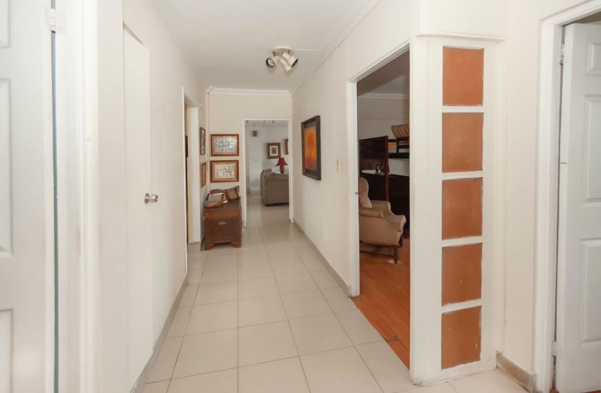 Wide hallway with tile floors, decorative alcoves, artworks and access doors at PH Majurova