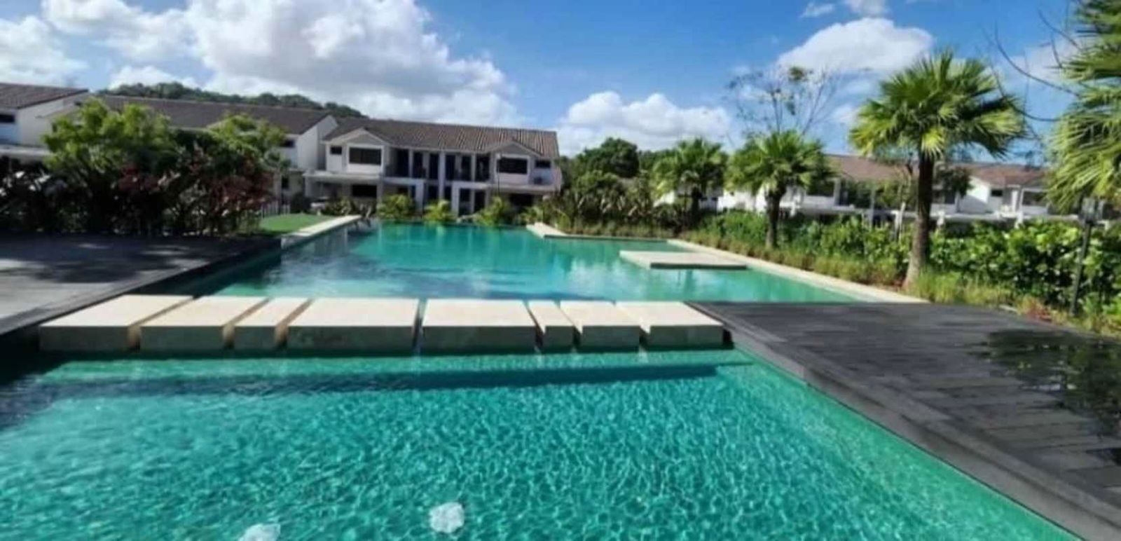 Community swimming pool with sun loungers, umbrellas, palm trees at PH Sierra Nevada Brisas del Golf Panama City