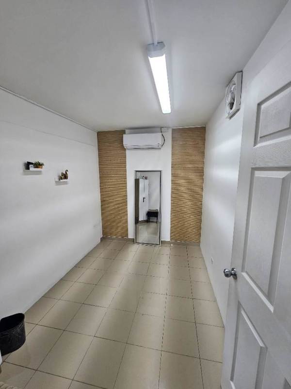 Compact room with air conditioner, mirror, and wood panel accent wall in Plaza El Carmen Panama City