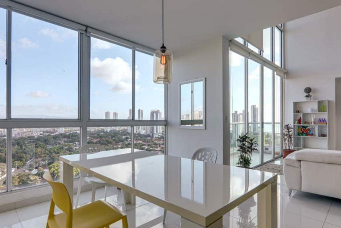 Dining area in loft apartment with high ceilings and city views Park Loft Panama City