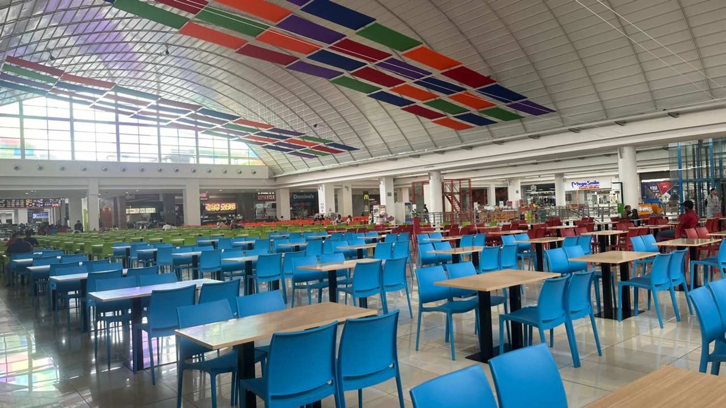 Spacious contemporary mall food court with colorful seating and large windows at Los Andes Panama City