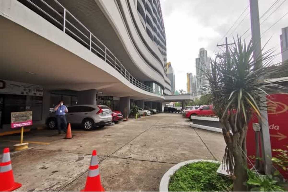 Modern commercial tower with curved glass facade and parking lot in El Cangrejo Panama City