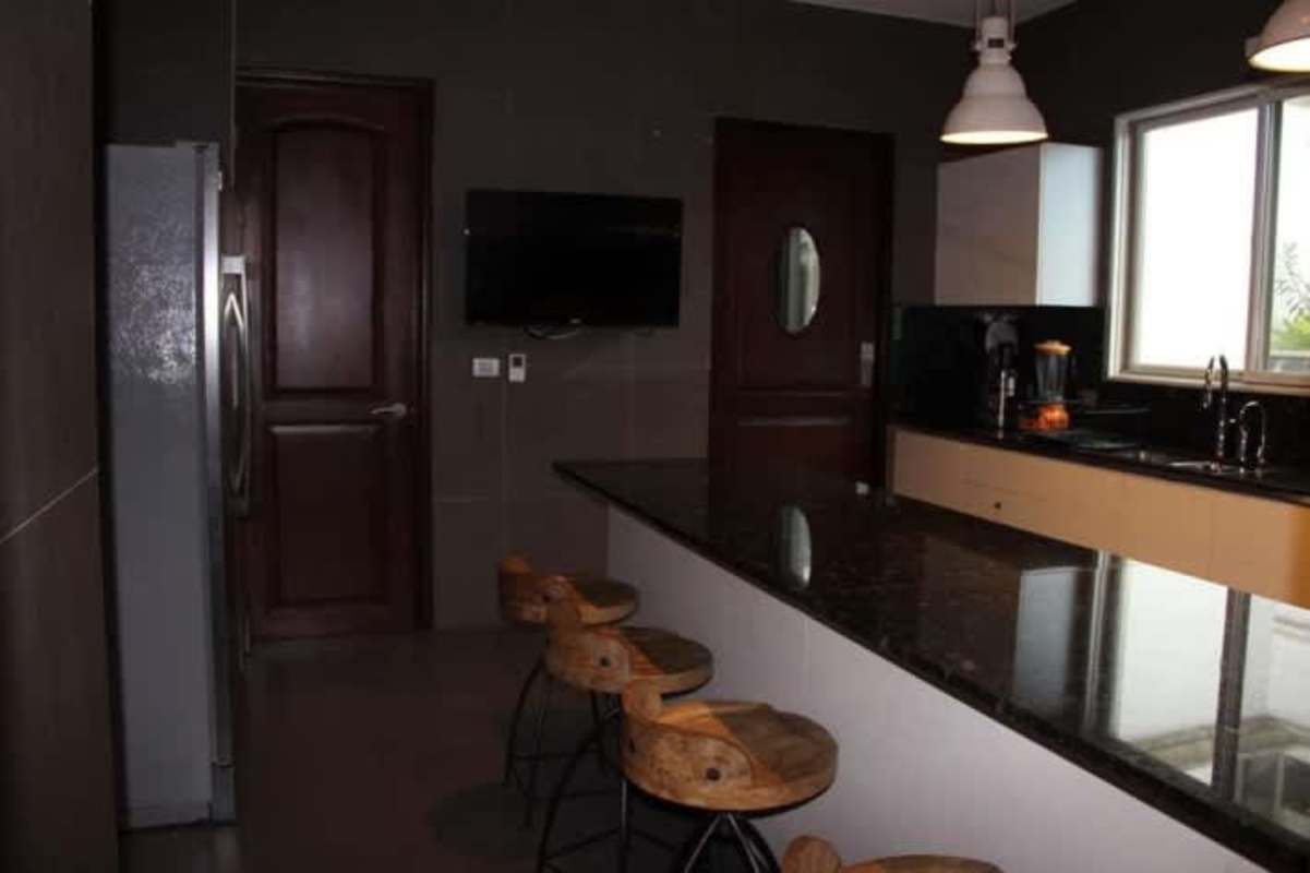 Modern kitchen with island, granite countertops, pendant lights, wood cabinetry Fairway Estates Panama