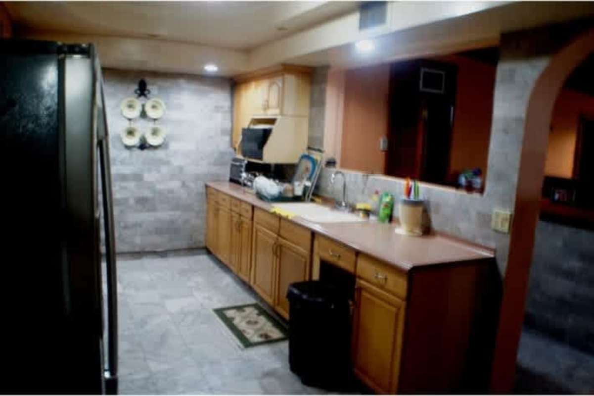 Kitchen with wooden cabinets, tile backsplash, and stone floor Los Rios Corozal Panama City