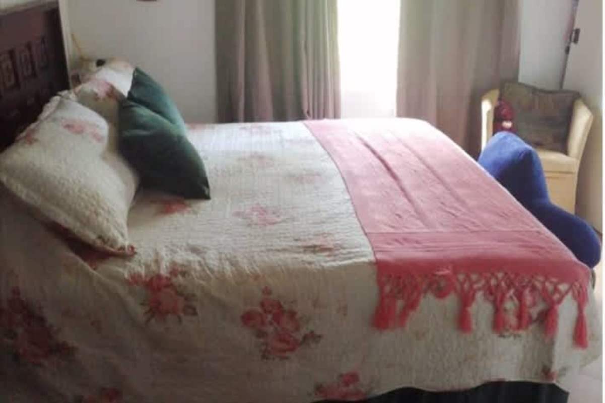 Bedroom with double bed, floral bedding, natural light in mountain house Panama