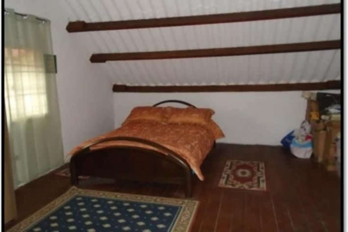 Attic-style bedroom with sloped ceiling, wood beams and wood floors Panama mountain home