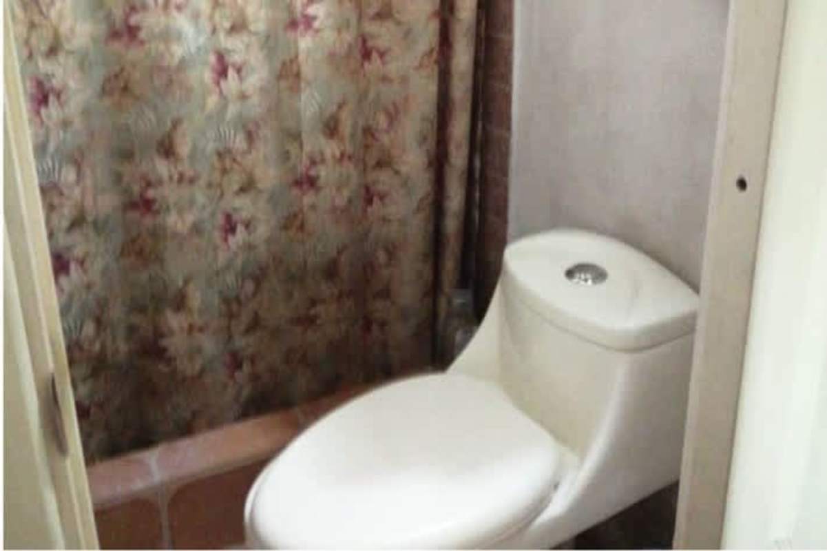 Small bathroom with floral shower curtain, compact fixtures in mountain home Panama