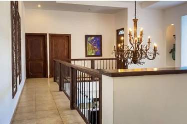 Mediterranean hallway with wood railing, chandelier, tile floors at Punta Barco estate
