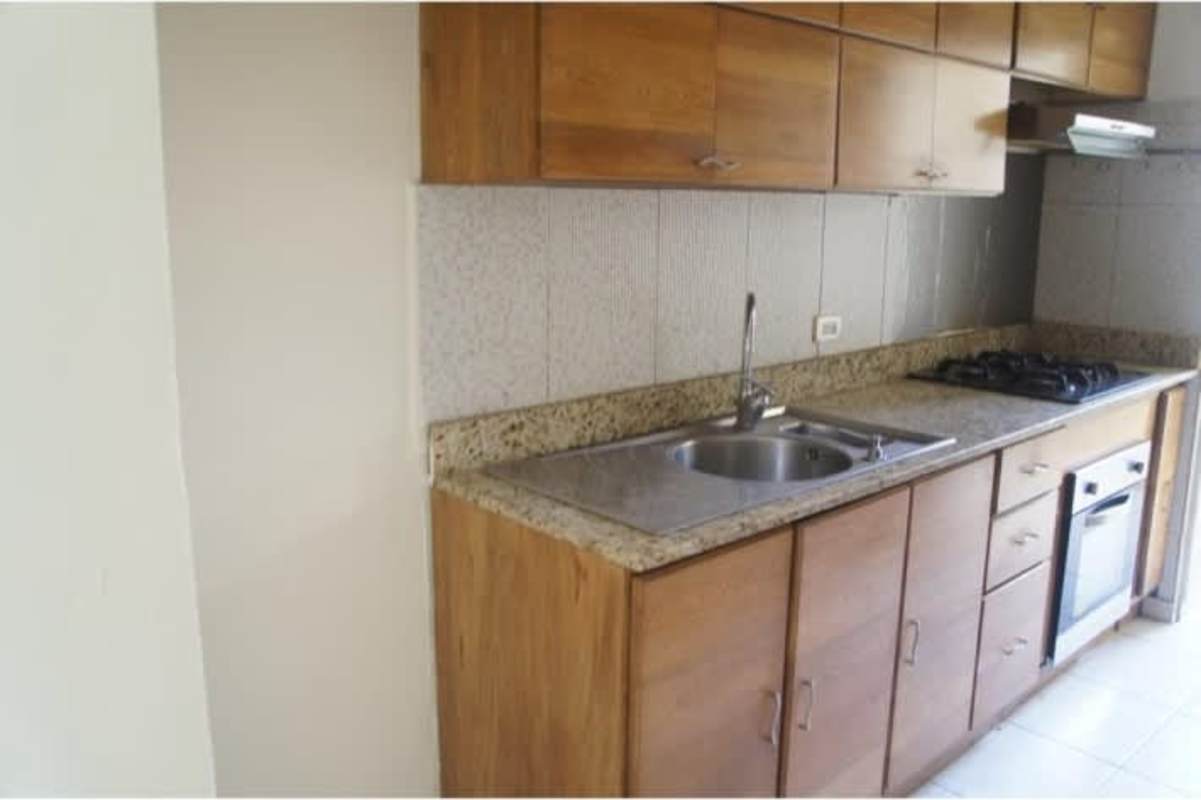 Apartment kitchen with granite countertops, wooden cabinetry, gas stove at PH Metro Park View Betania Panama City
