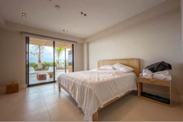 Bright guest bedroom with large window and tropical garden view at Punta Caelo penthouse Panama
