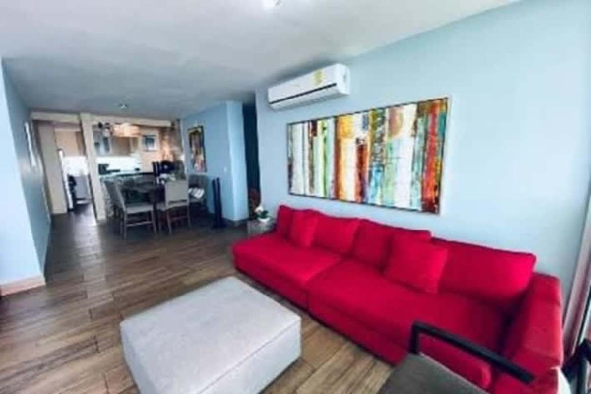 Open plan living, dining and kitchen space with red sofa, artwork, and modern furnishings in PH The Regent San Francisco Panama