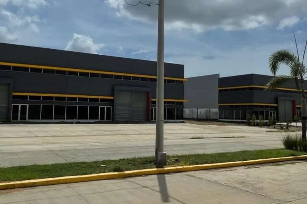 Industrial warehouse front with roller shutters, glass door entrance, concrete pavement Juan Díaz Panama