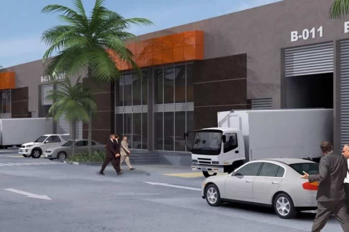 Warehouse exterior with loading bays, delivery trucks, palm trees, and parking at 24 de Diciembre Panama