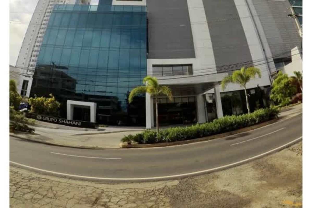 Main entrance of Panama Business Tower with glass facade and landscaped palm trees Obarrio Panama City