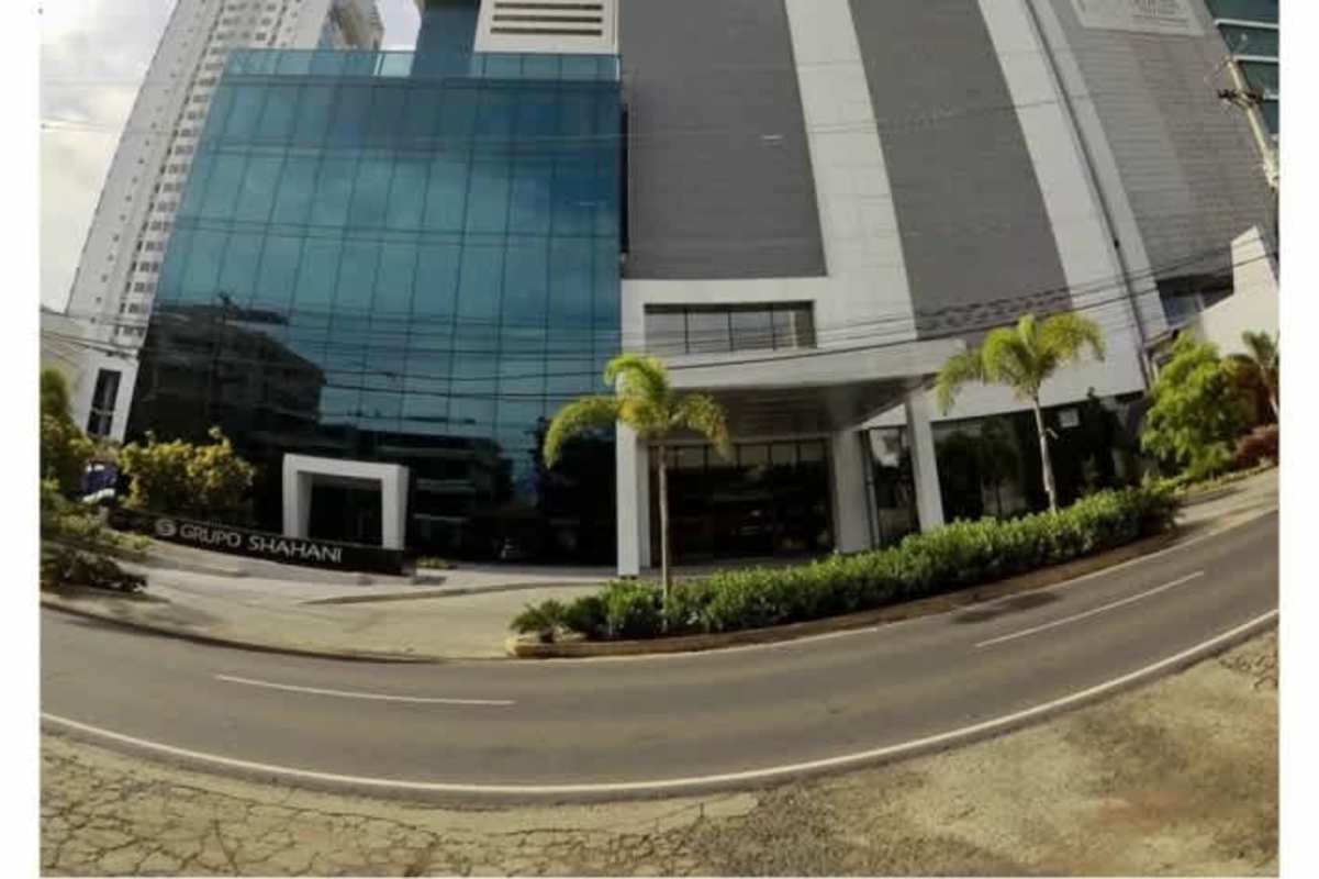 Canopy entrance with tall glass facade and palm trees PH Panama Business Tower Panama City