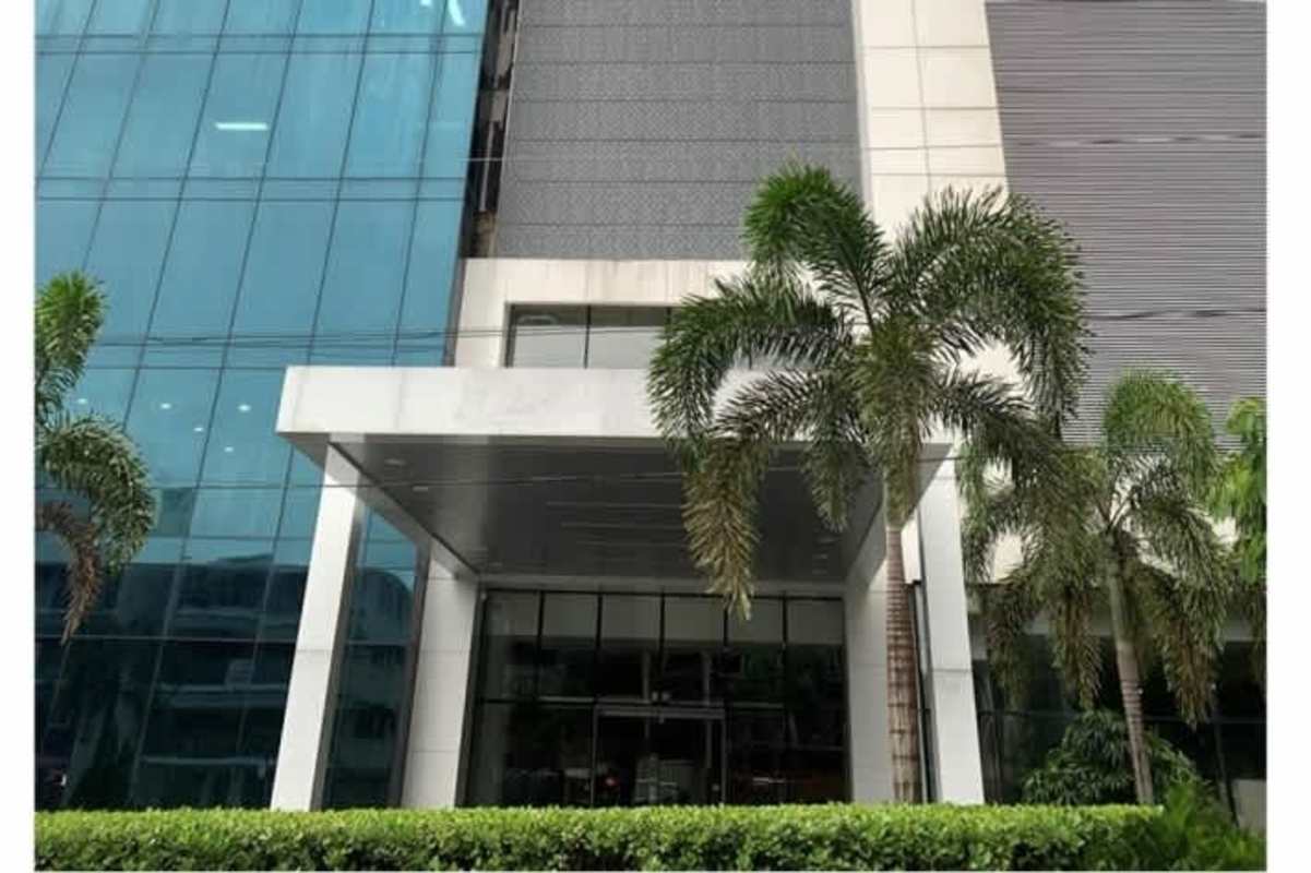 Modern corporate building exterior with glass facade, entrance canopy and palm trees Panama City