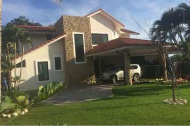 Two-story Mediterranean villa with red-tiled roof, stone wall, carport, lush landscaped garden in Coronado Panama