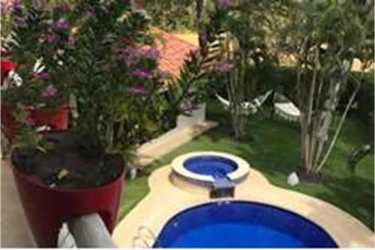 Two-story Mediterranean villa with red tile roof, gated entry and palm trees in Coronado Panama