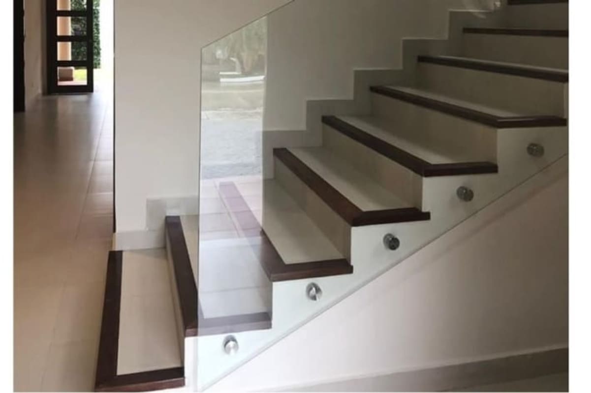 Floating glass-railed staircase with wood accents inside El Doral Costa Sur Panama house