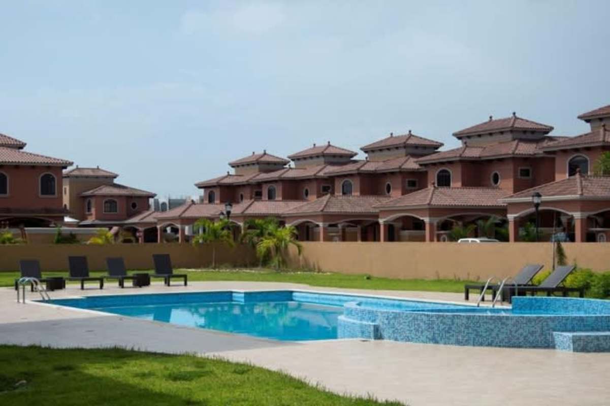 Small backyard with green lawn, tile patio and vertical garden in El Doral Costa Sur Panama house