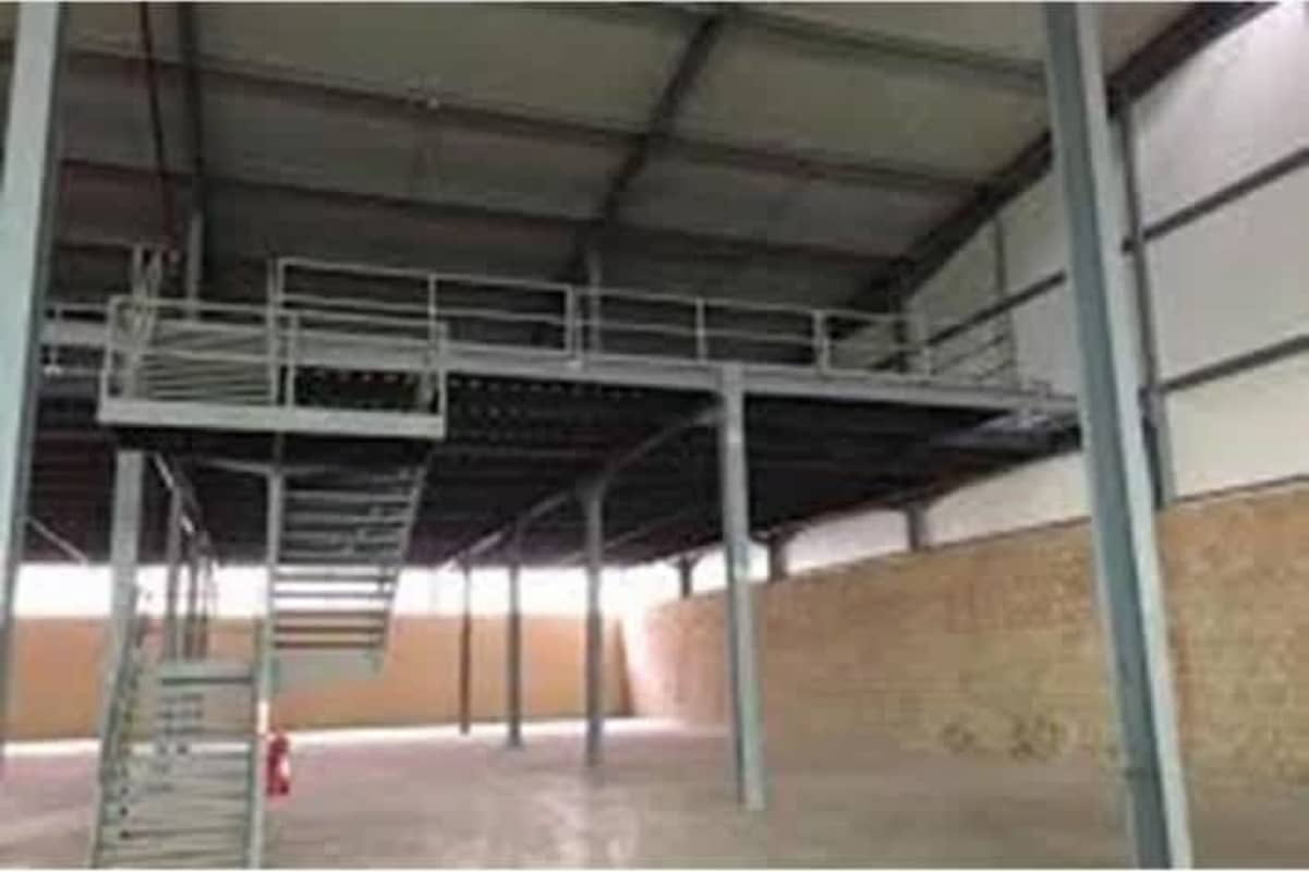 Interior industrial warehouse space with metal mezzanine, stairs, brick wall and high ceiling Parque Industrial Panama