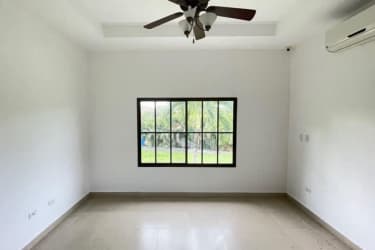 Empty room with tiled floor, ceiling fan, arched window in Hacienda Pacifica San Carlos