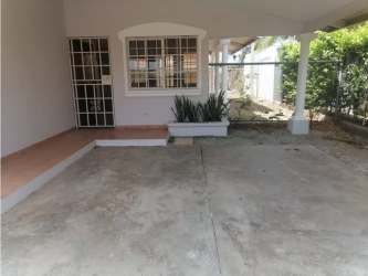 Covered parking area and entrance with plants in Chitré single-family home