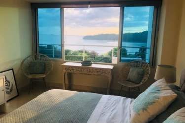 Bedroom with woven chairs, decorative console, large window with Pacific view in Casa Bonita Playa Bonita Panama