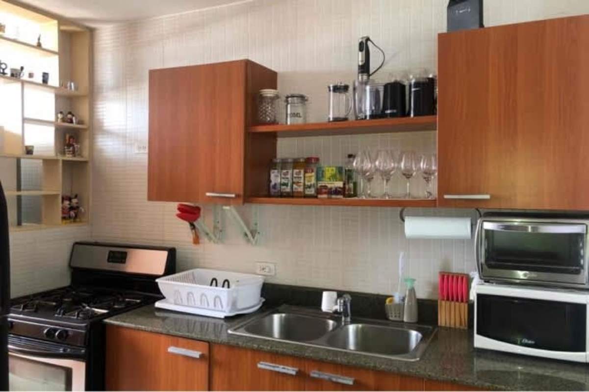 Functional kitchen with cabinets, shelves, granite countertop, and appliances in Panama City