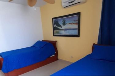 Beachfront high-rise with palm trees, umbrellas, lounge chairs by lagoon at PH El Peñón de Farallón