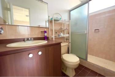Bathroom with beige tiles, glass door shower, mirror and storage