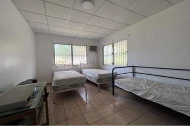 Simple bedroom with tiles, air conditioning, security bars, garden view