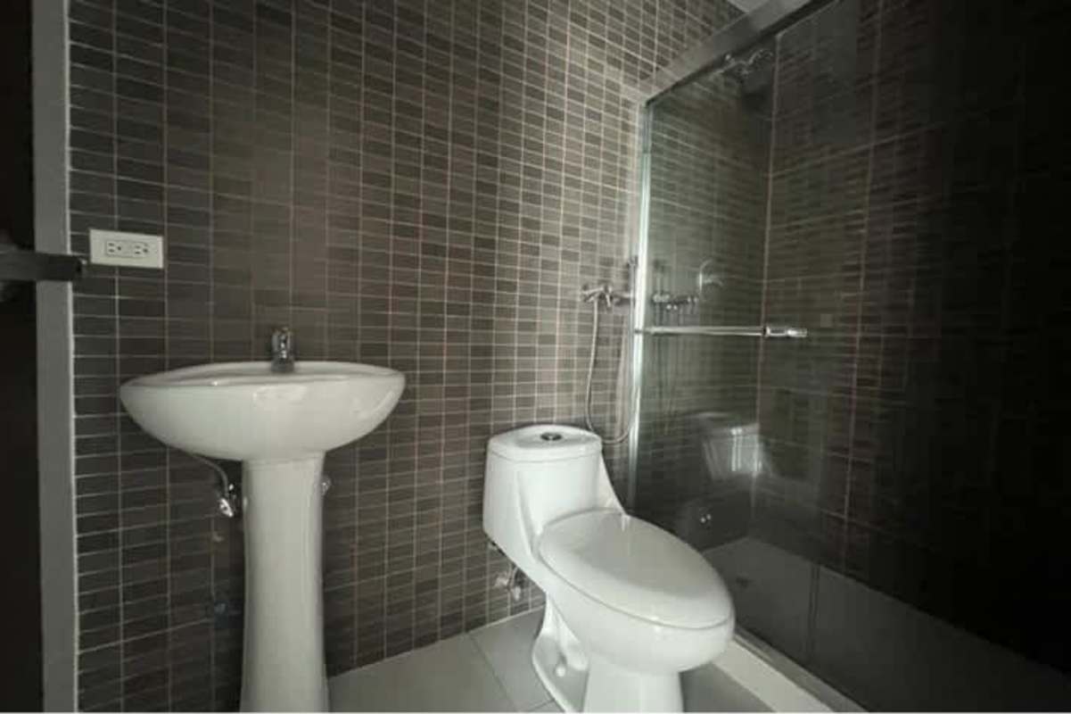 Bathroom with gray tiles, pedestal sink, toilet and glass enclosure at PH El Cangrejo