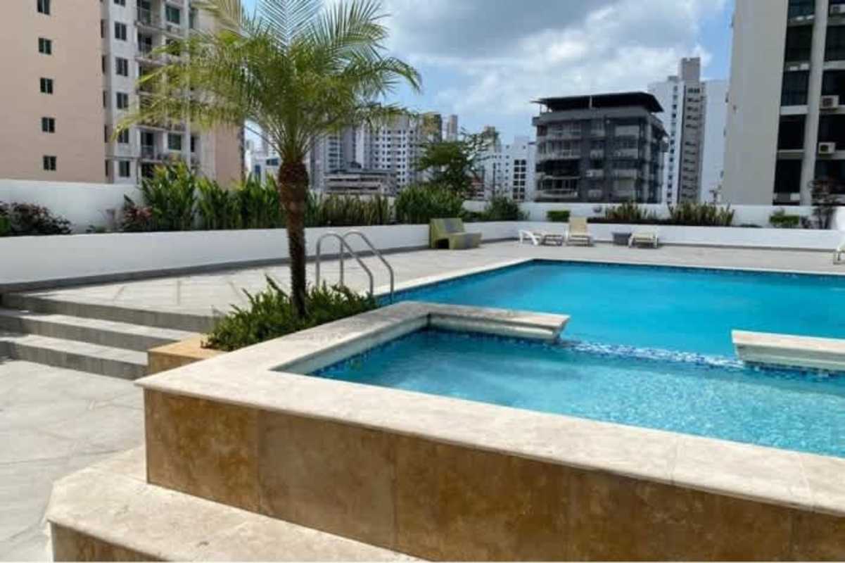 Outdoor swimming pool with palm trees and skyline views at PH El Cangrejo Panama