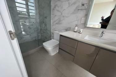 Spacious modern bathroom with large glass shower, marble wall tile, sleek vanity Explora Panama Pacifico