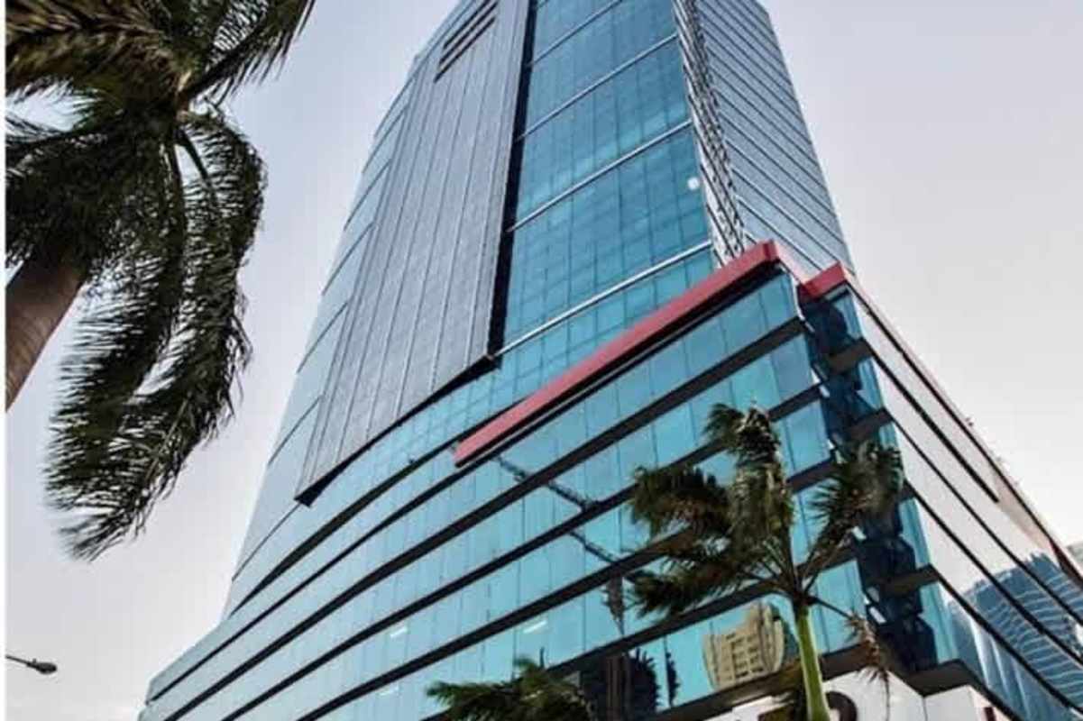 Modern high-rise commercial tower with reflective glass facade palm trees Costa del Este Panama