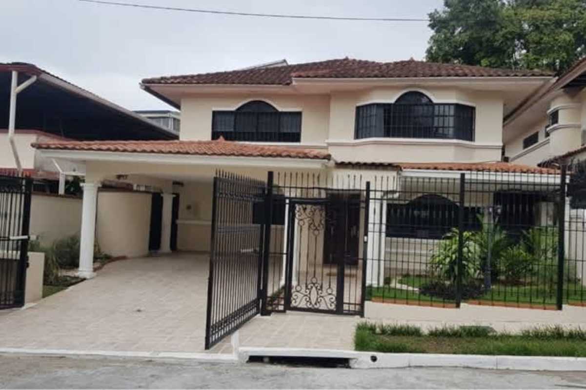 Exterior view of two-story Mediterranean inspired house with tile roof and iron gate in La Alameda Betania