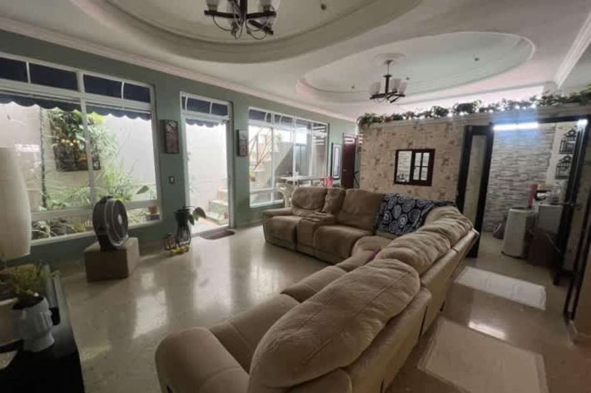 Spacious bright living room with stone accent wall sectional sofa and large windows at Colinas del Golf, Panama