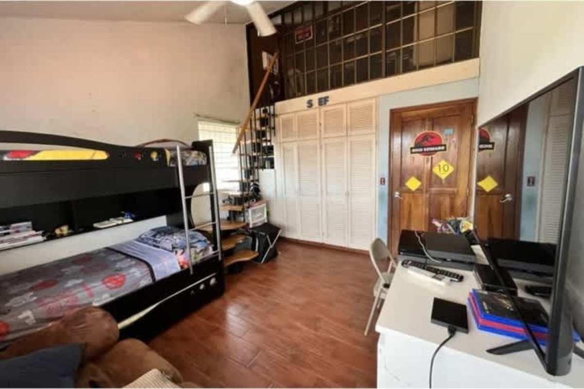 Covered terrace with wicker furniture, ceiling fans, stone wall, garden view in Altos de Panama home