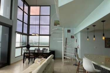 Open plan double-height living area with spiral stairs, coastal scenery, in PH Biltmore penthouse Nueva Gorgona Panama