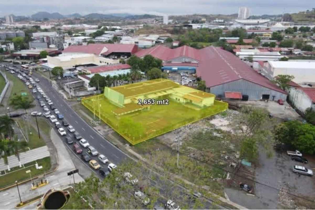 Aerial image of fenced industrial warehouse with metal roofs and driveway in Juan Díaz main road Panama City