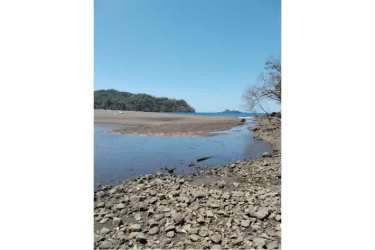 Wide stretch of sandy beach with rocky coastline and blue Pacific waters Punta Naranjo