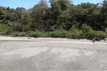 Natural rocky riverbank with shallow water and distant hills Punta Naranjo