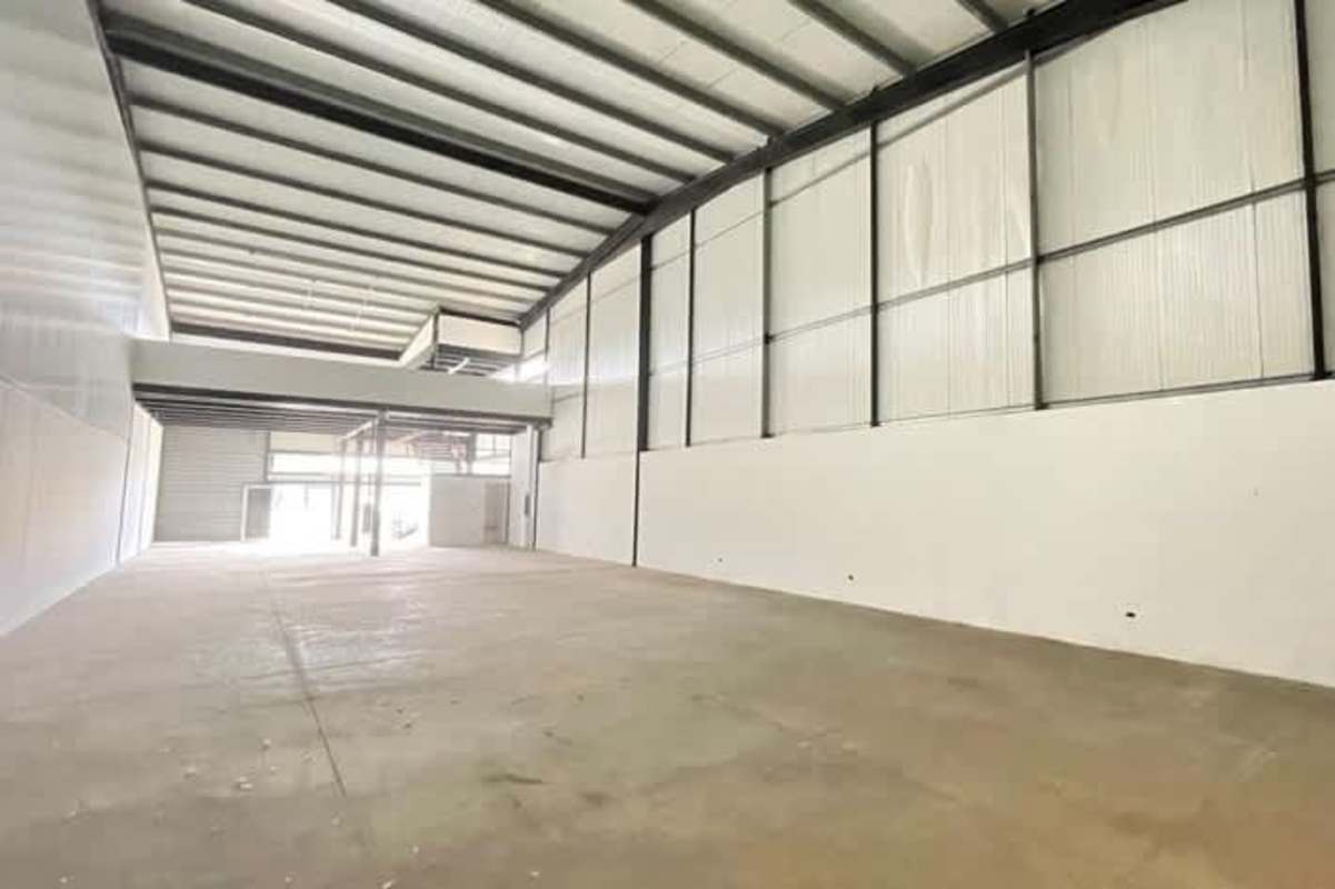 Empty industrial warehouse space with concrete floor, high ceiling, steel beams and roller shutter entrance in Juan Díaz Panama