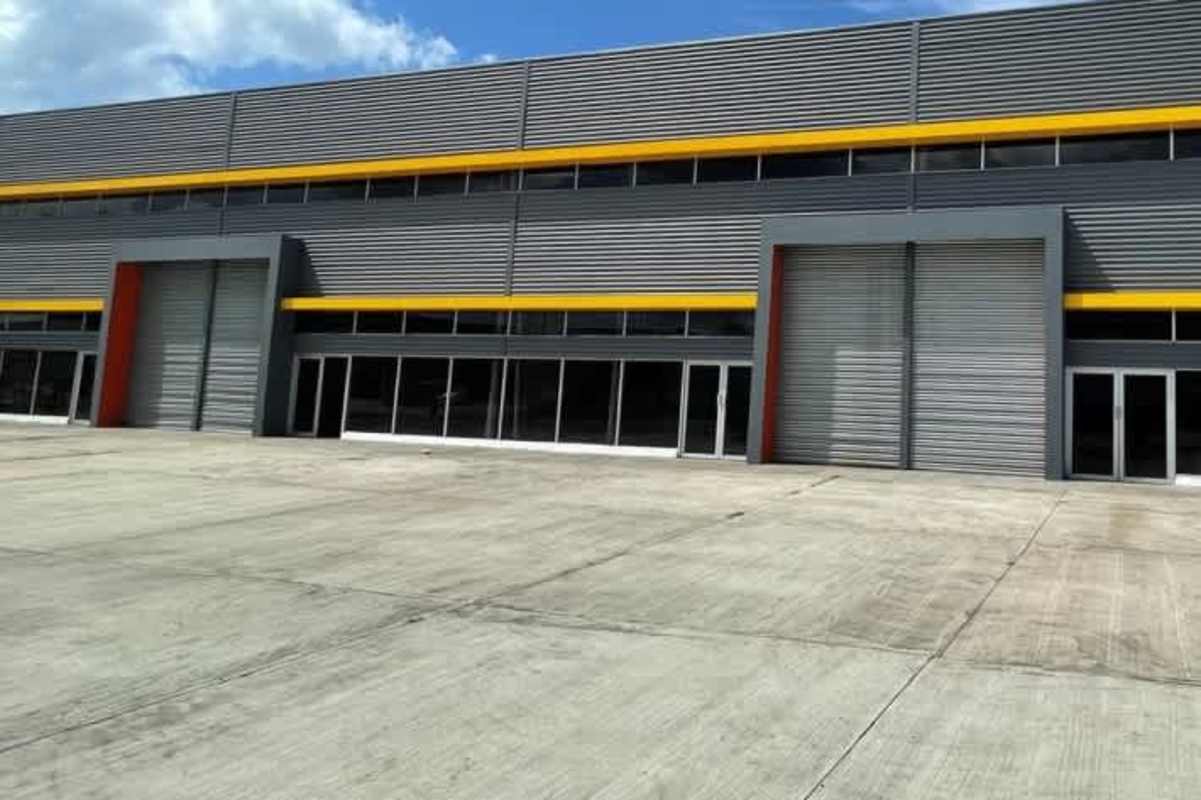 Modern industrial warehouse exterior with loading dock, roller shutter doors and driveway in Panama Juan Díaz industrial park