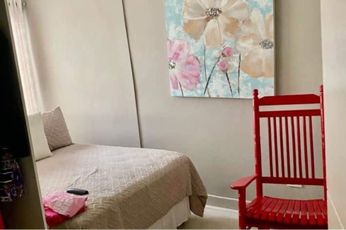 Small bedroom with neutral tones, floral art, red rocker in Betania Panama house for sale