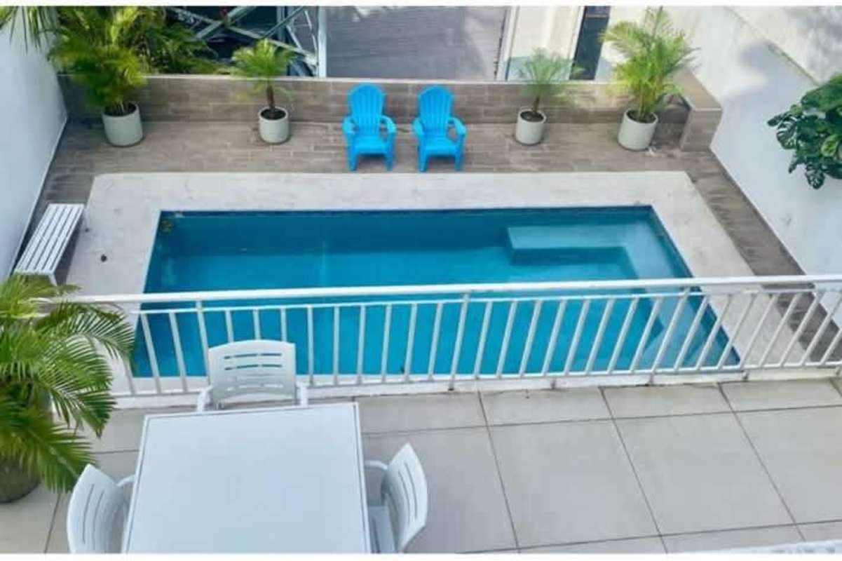 Modern patio with swimming pool, blue chairs, white railing in La Alameda Betania Panama house