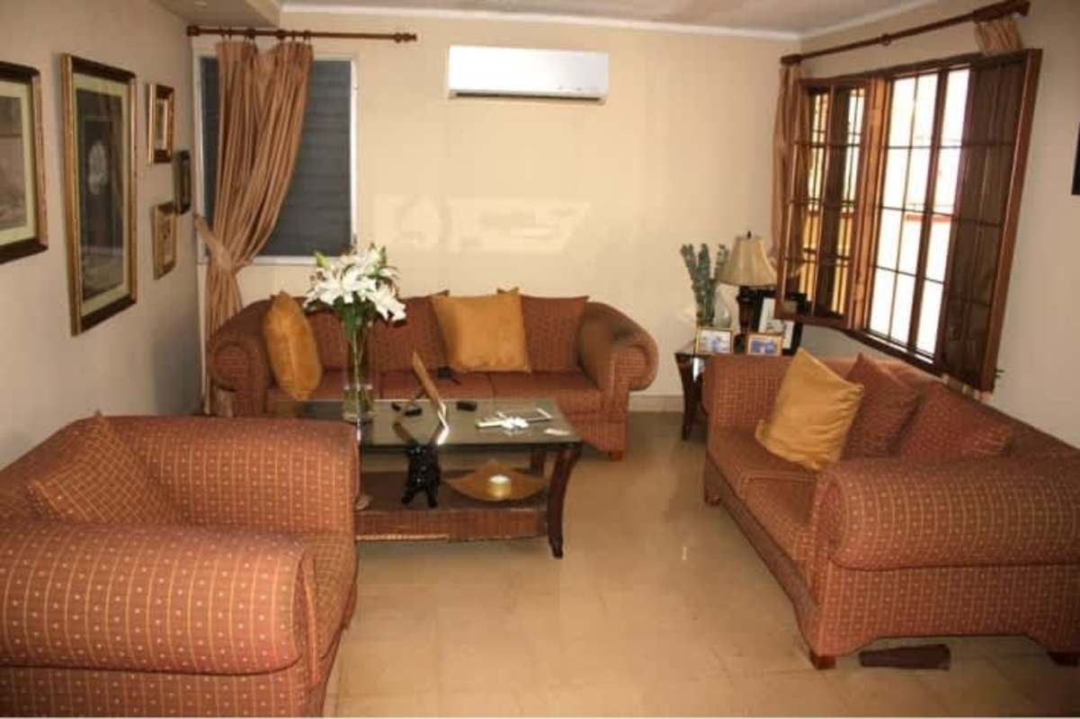 Traditional living room with large windows, sofas, tiled floor, and AC in Panama City house