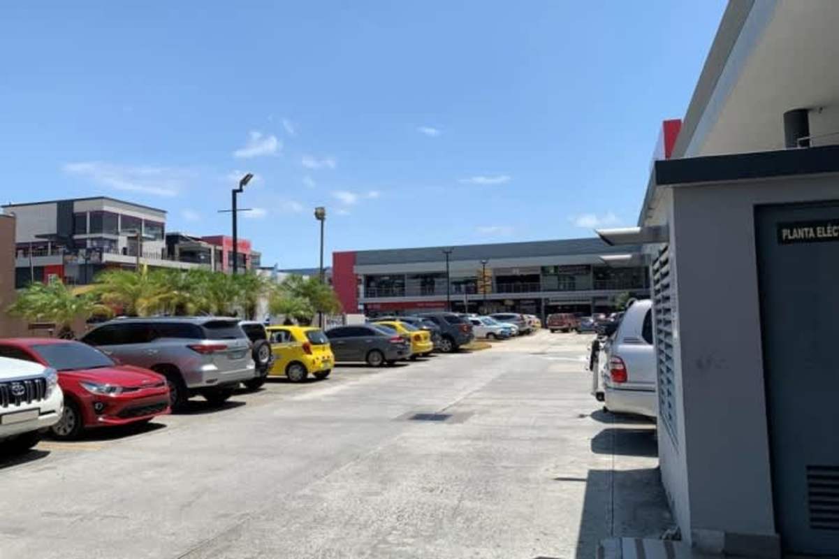 Large parking lot with palm trees and retail shops at Centennial Plaza Panama City