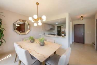 Modern dining space next to open kitchen with chandelier and mirror